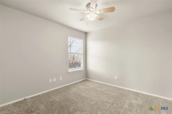 an empty room with a window and a fan