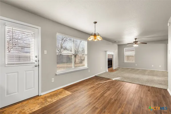 a view of an empty room with window and wooden floor