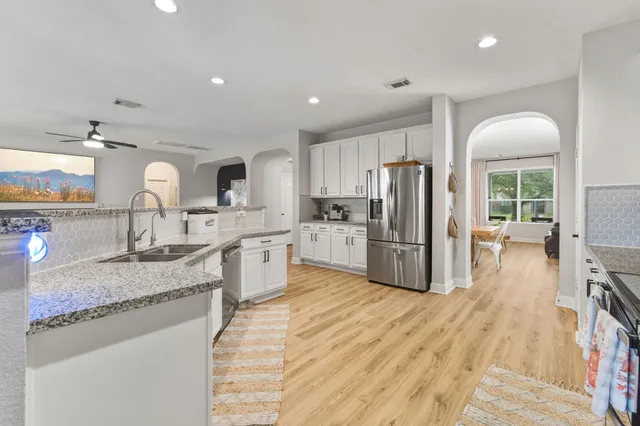 a large kitchen with stainless steel appliances granite countertop a lot of counter space and wooden floors