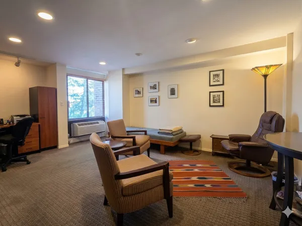 a living room with furniture a desk and chair with a bookshelf