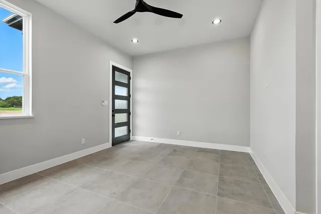 an empty room with windows and ceiling fan