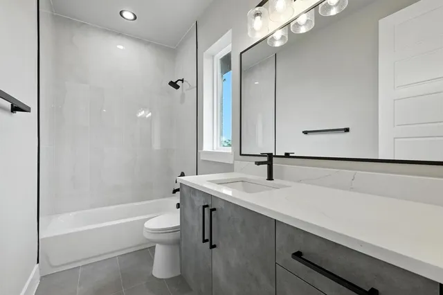 a bathroom with a granite countertop sink a toilet and shower