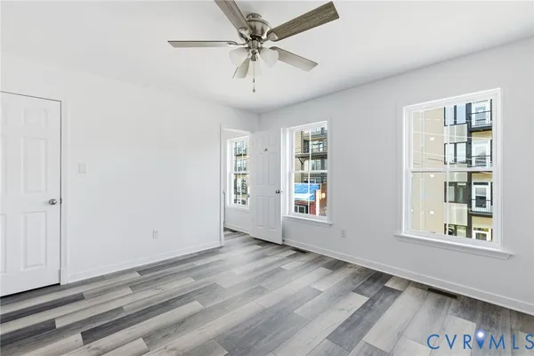 a view of an empty room with window and wooden floor