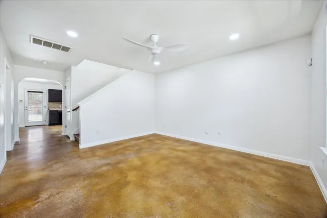 an empty room with a chandelier fan and windows