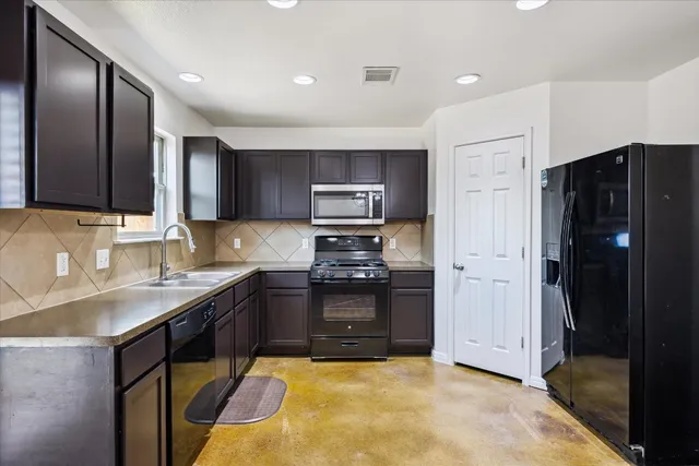 a kitchen with stainless steel appliances granite countertop a stove refrigerator and sink