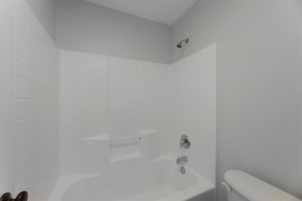 605 Clearbrook Street Azle, TX 76020 - Photo 22 of 33 Bathtub and shower combination featuring white subway tile surround, chrome fixtures, and an integrated shelf