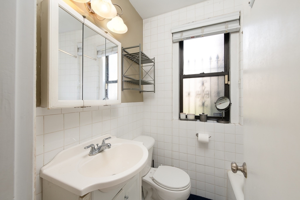 64 Queensberry Street, Unit 101 Boston, MA 02215 - Photo 5 of 10 a bathroom with a sink mirror and a toilet