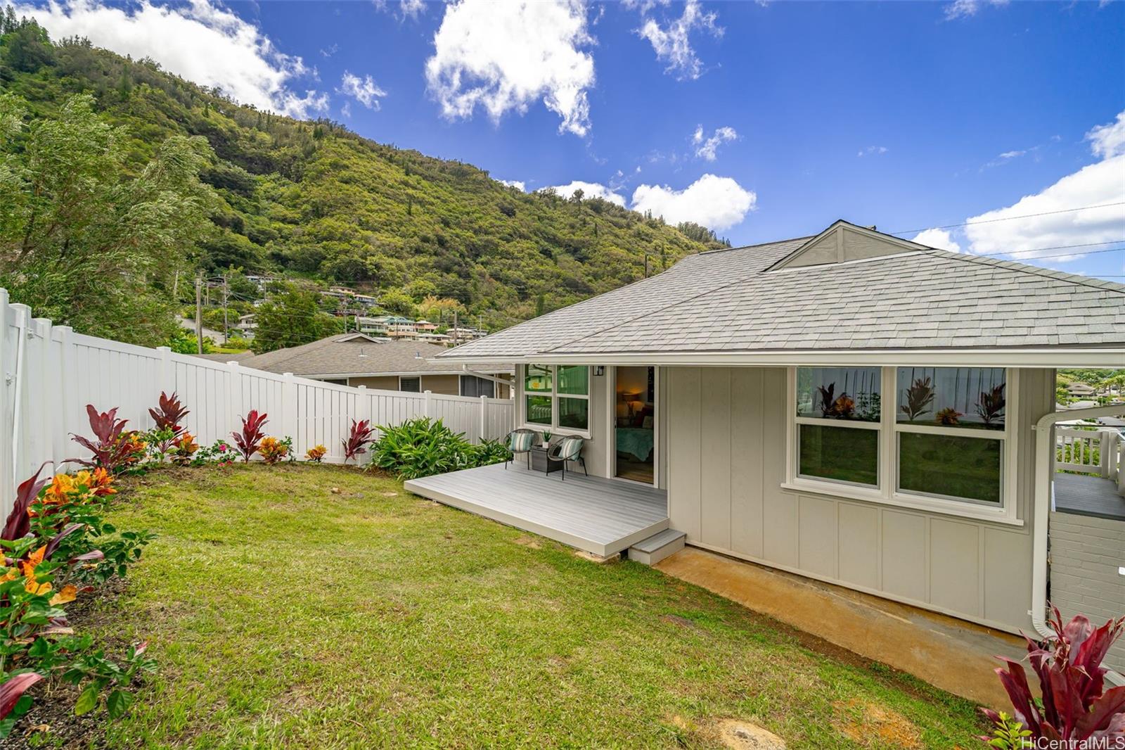 Good-sized, newly landscaped & fully fenced backyard and composite deck, from primary bedroom. Manoa Valley hillside views at back.