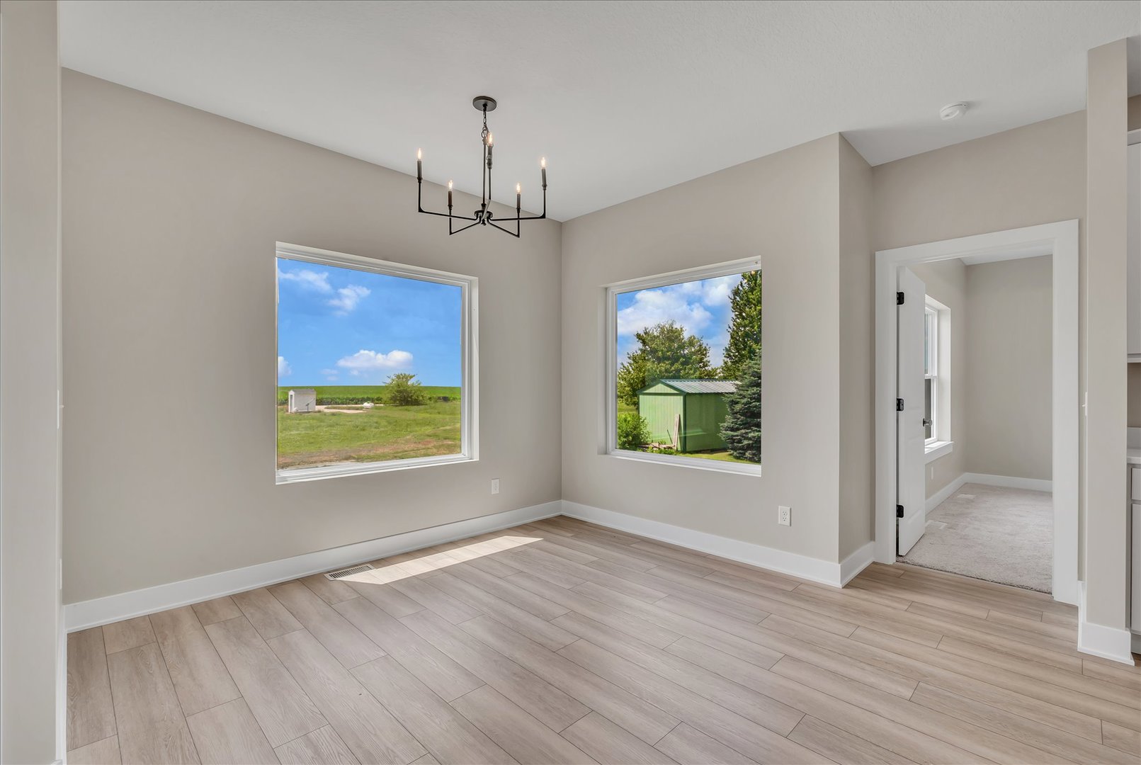 455 Rhonda Road New Liberty, IA 52765 - Photo 27 of 54 an empty room with wooden floor a chandelier and windows