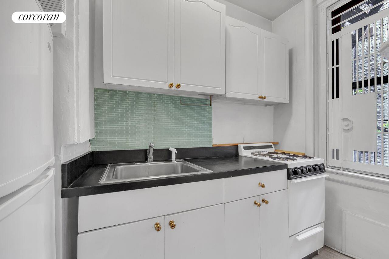 17 West 64th Street, Unit 2E Manhattan, NY 10023 - Photo 4 of 5 a kitchen with granite countertop white cabinets and white appliances