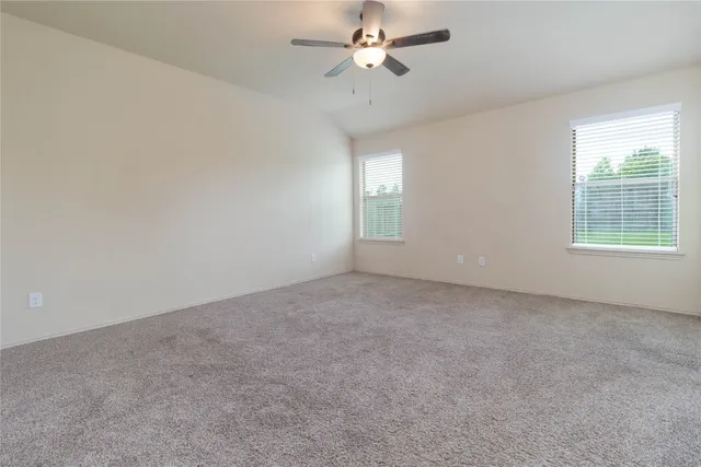 an empty room with a window and ceiling fan