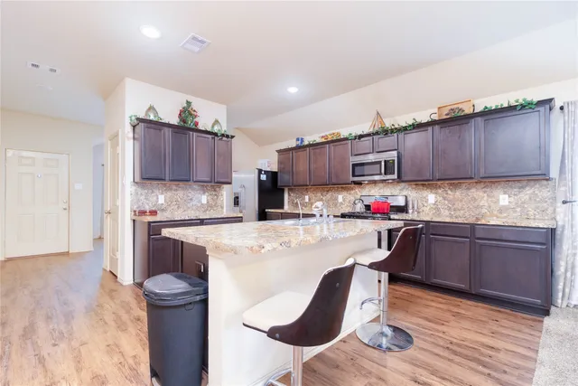 a kitchen with granite countertop wooden floors and wooden cabinets