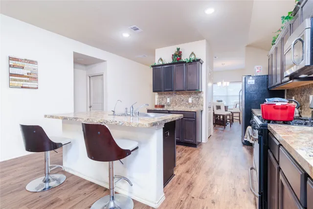 a kitchen with kitchen island granite countertop wooden floors and a view of living room