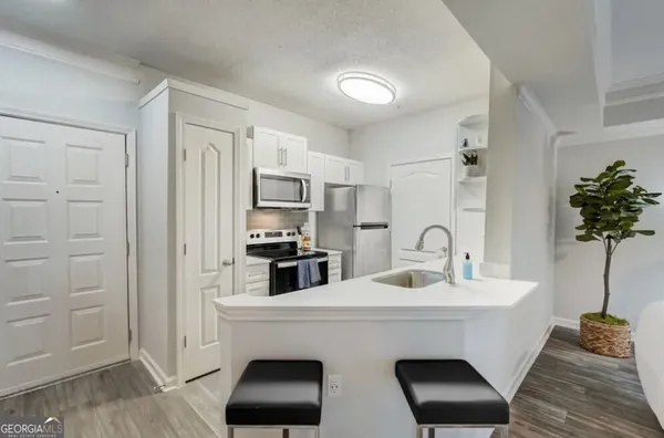 a kitchen with stainless steel appliances a sink a stove a refrigerator cabinets and wooden floor