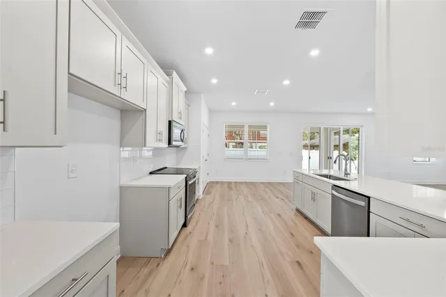 a kitchen with granite countertop a sink a stove refrigerator and cabinets