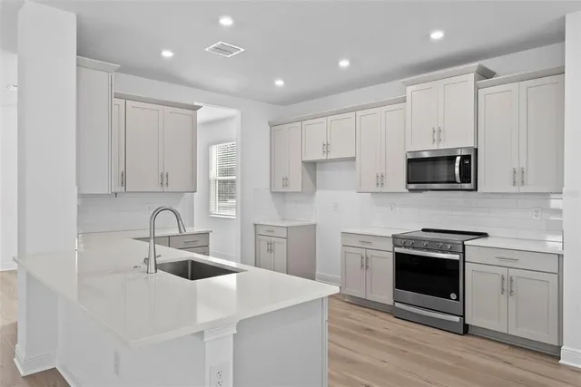 a kitchen with white cabinets stainless steel appliances and sink