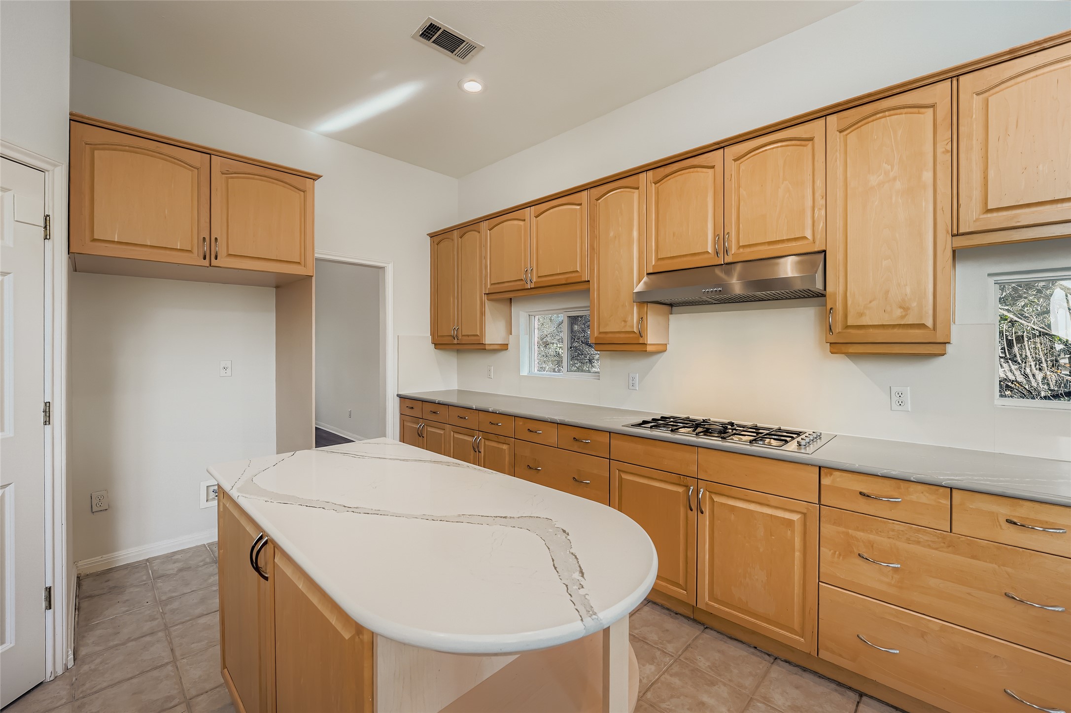 8204 Texas Plume Road Austin, TX 78759 - Photo 15 of 40 Kitchen with a center island, under cabinet range hood, light tile patterned flooring, light stone counters, and recessed lighting