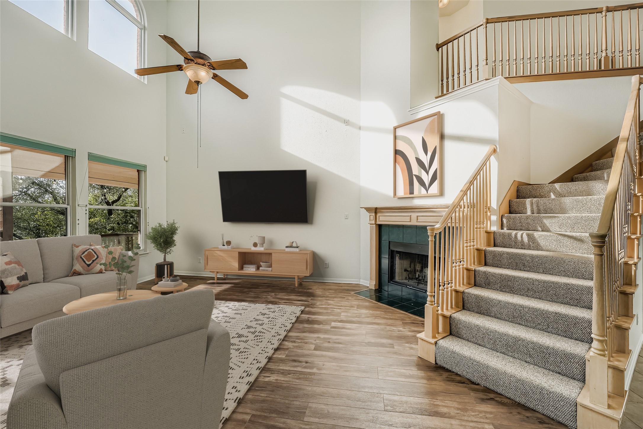8204 Texas Plume Road Austin, TX 78759 - Photo 6 of 40 Living room with a towering ceiling, hardwood / wood-style floors, a ceiling fan, a tiled fireplace, and stairs