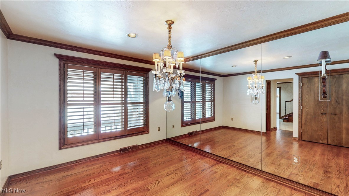 1091 Sand Run Road Akron, OH 44313 - Photo 5 of 26 Formal dining rm showcases a spectacular crystal chandelier, mirrored wall, sconces, wood floor, china cabinet closet & windows with wood plantation shutters.