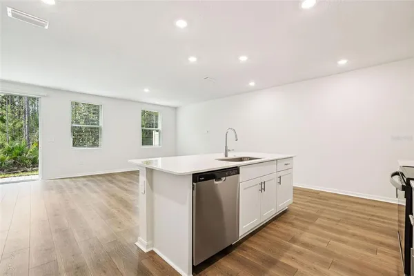 a large kitchen with a center island wooden floor and stainless steel appliances