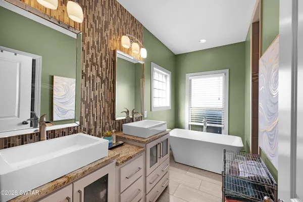 a spacious bathroom with a double vanity sink a mirror and a bathtub