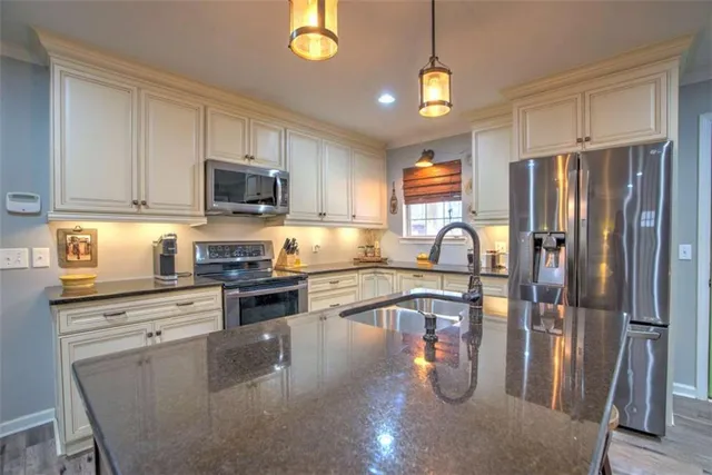 a kitchen with stainless steel appliances granite countertop a refrigerator a stove top oven a sink and dishwasher