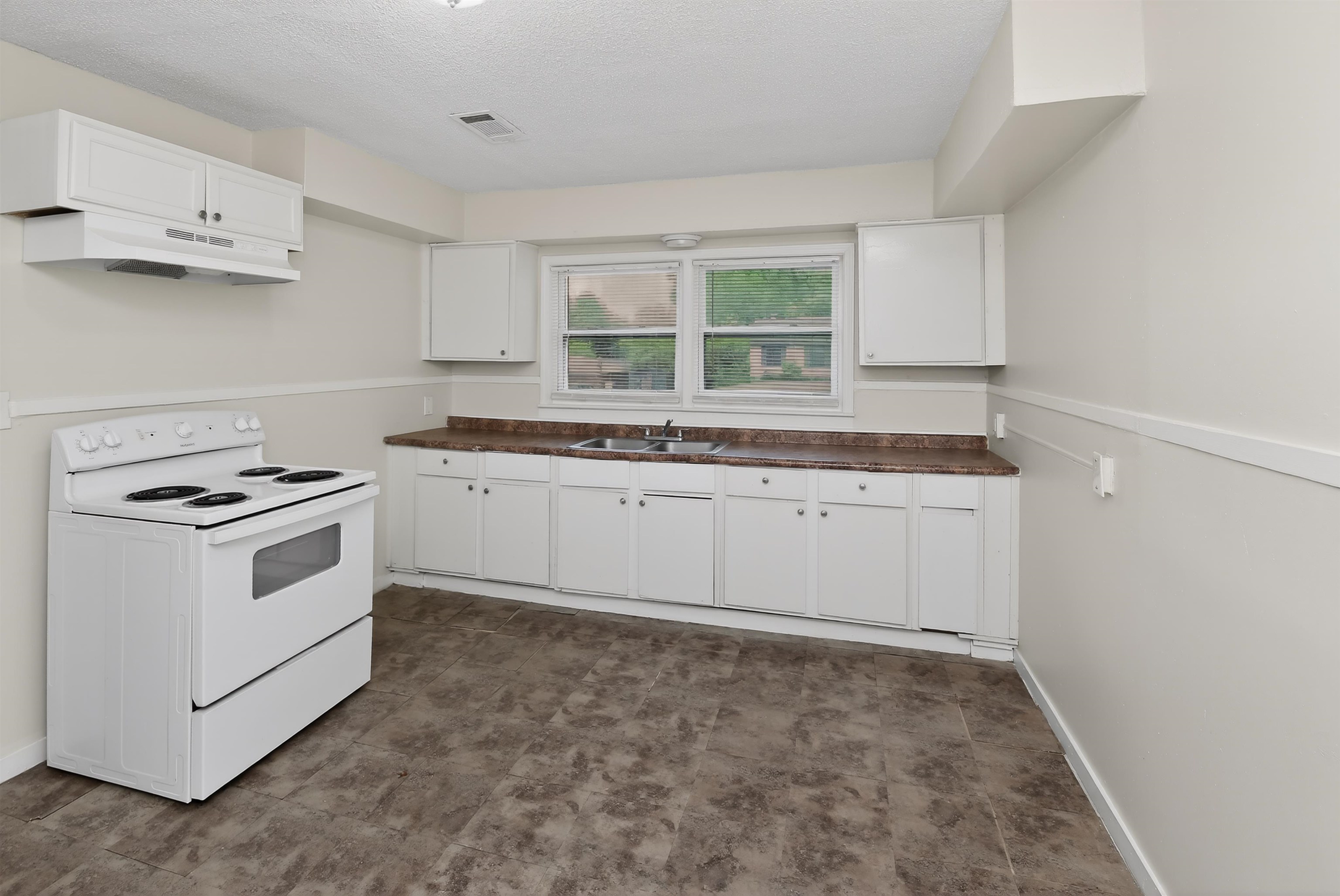 318 East Raines Road Memphis, TN 38109 - Photo 21 of 28 Kitchen featuring white cabinetry, a white electric range, and a dual-basin stainless steel sink