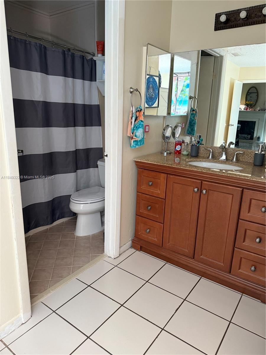 13402 Southwest 116th Place Miami, FL 33176 - Photo 10 of 16 a bathroom with a sink a toilet a mirror a shower and a window