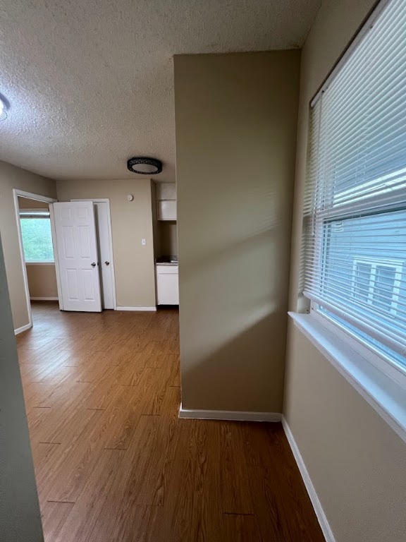Corridor featuring dark wood-style floors and a textured ceiling