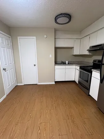 a large kitchen with a wooden floor and stainless steel appliances