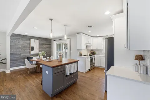 a kitchen with stainless steel appliances granite countertop a stove a refrigerator a sink dishwasher and a dining table with wooden floor