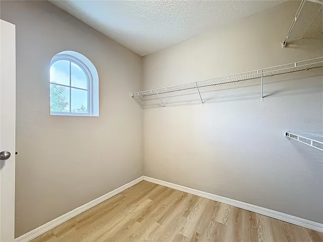 a view of a hallway with wooden floor and a bathroom