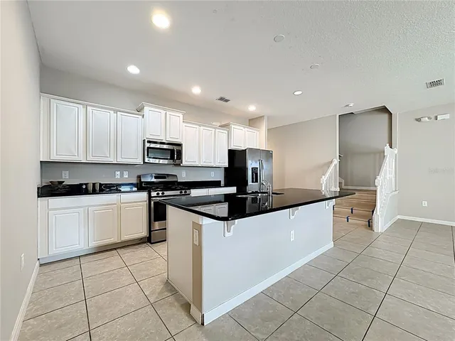 a kitchen with stainless steel appliances granite countertop a sink and a refrigerator