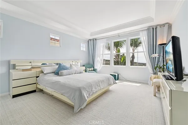 a bedroom with a bed and a flat tv screen on the dresser