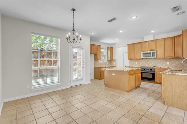a large kitchen with kitchen island granite countertop a stove a sink a counter space and cabinets