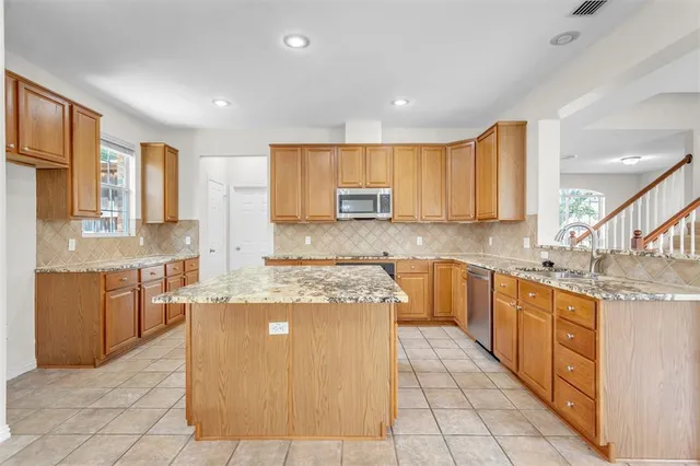 a large kitchen with stainless steel appliances granite countertop a stove a sink dishwasher and a refrigerator