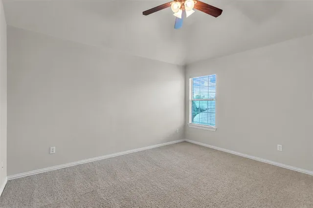 an empty room with a chandelier fan and windows