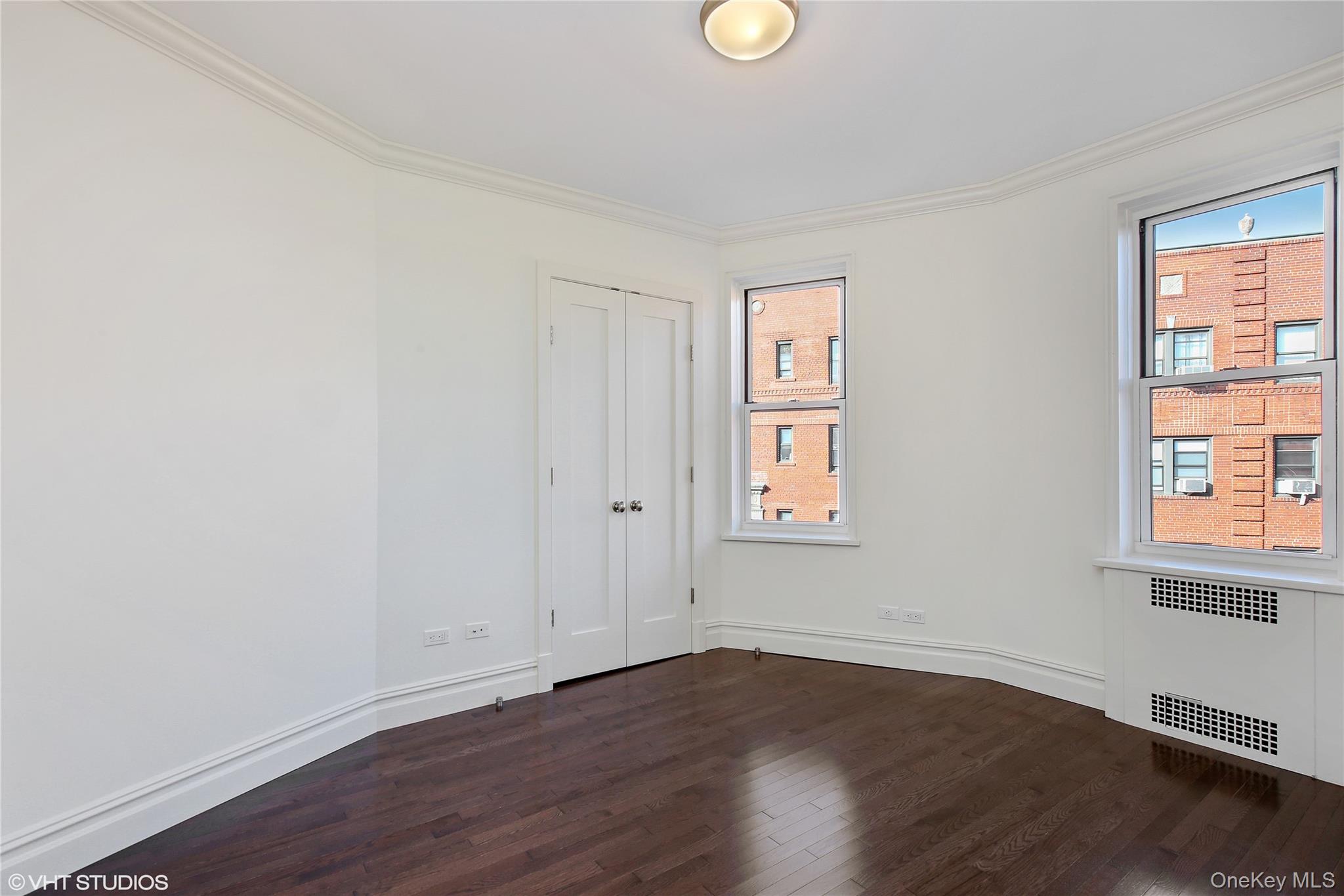 73-12 35th Avenue, Unit D2 Queens, NY 11372 - Photo 5 of 15 an empty room with wooden floor and windows