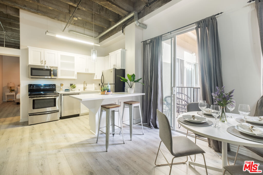 312 West 5th Street, Unit 606 Los Angeles, CA 90013 - Photo 2 of 18 a kitchen with kitchen island a dining table chairs stainless steel appliances and a large window