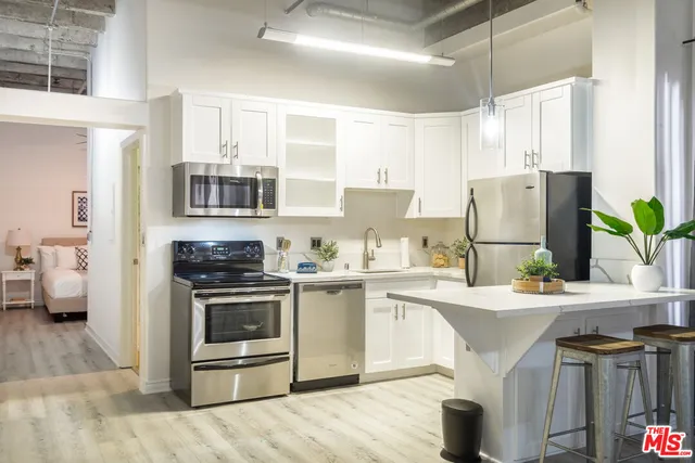 a kitchen with stainless steel appliances a stove a sink dishwasher a refrigerator and a stove