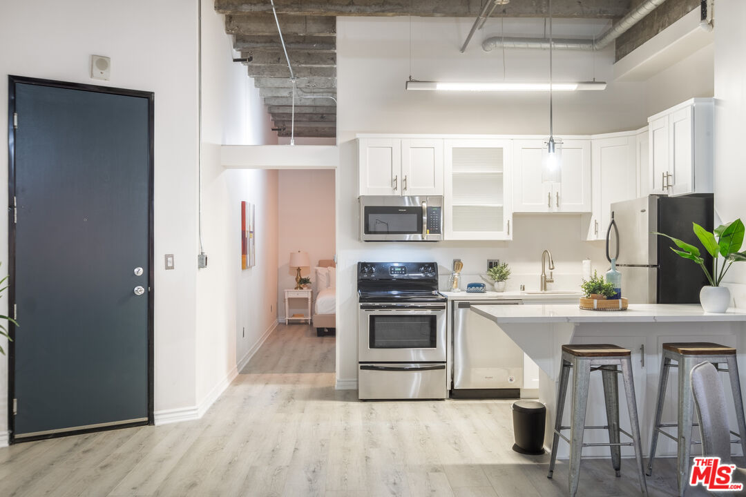 312 West 5th Street, Unit 606 Los Angeles, CA 90013 - Photo 7 of 18 a kitchen with granite countertop a stove a sink and a refrigerator