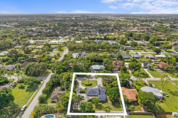 an aerial view of residential houses with outdoor space and trees