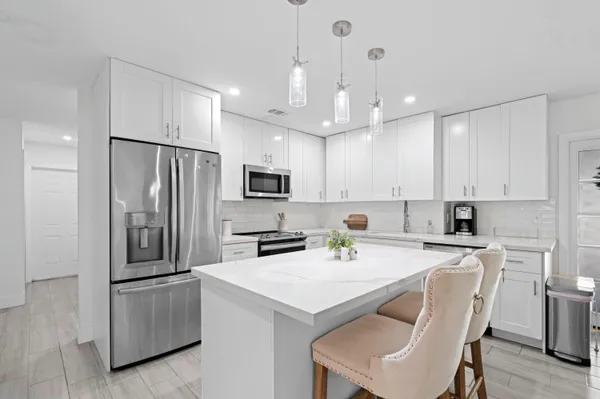 a kitchen with a refrigerator a stove a sink and chairs