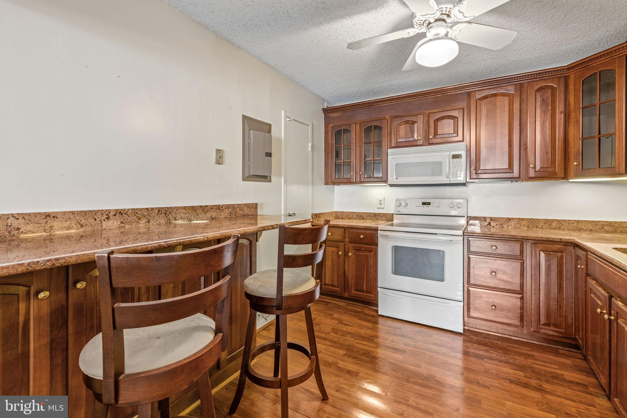 205 East Joppa Road, Unit 1606 Towson, MD 21286 - Photo 23 of 33 a kitchen with a stove a sink and white cabinets with wooden floor
