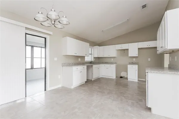 a kitchen with white cabinets and chandelier