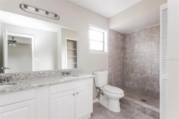 a bathroom with a granite countertop toilet a sink and a mirror