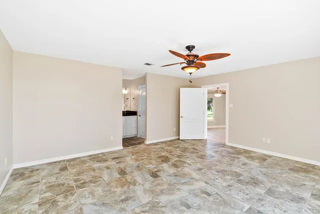 an empty room with window and ceiling fan