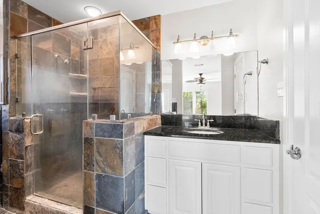 a bathroom with a granite countertop sink a mirror and shower
