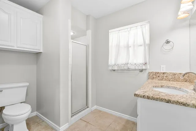 a bathroom with a granite countertop sink and a toilet