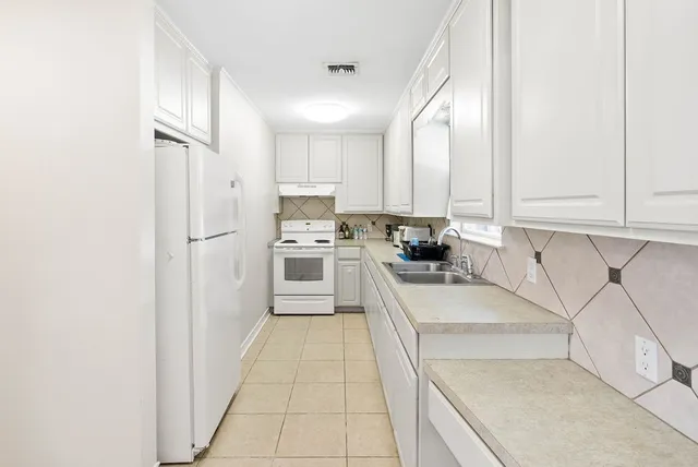 a kitchen with stainless steel appliances granite countertop a refrigerator sink and white cabinets